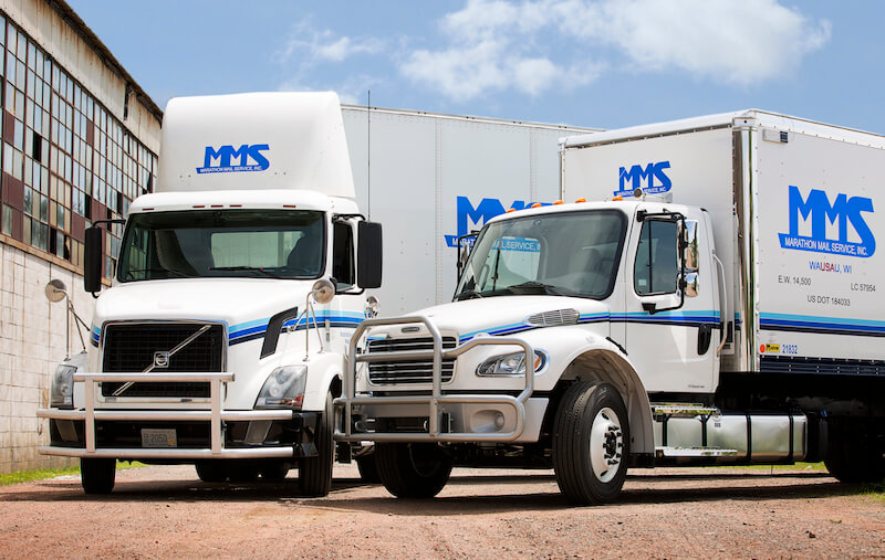 Two MMS Trucks in front of a warehouse